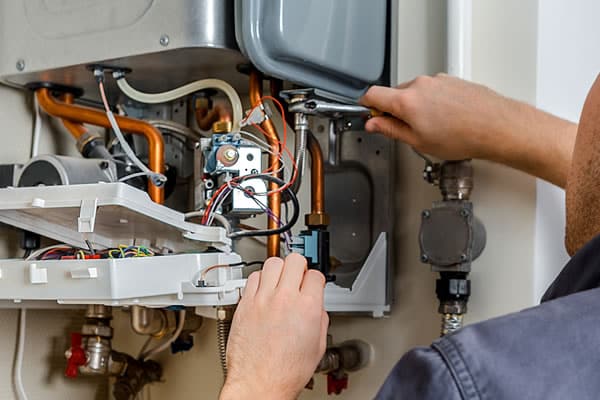 Technician reviewing maintenance checklist while servicing a complex boiler system in a Bellevue, WA apartment building