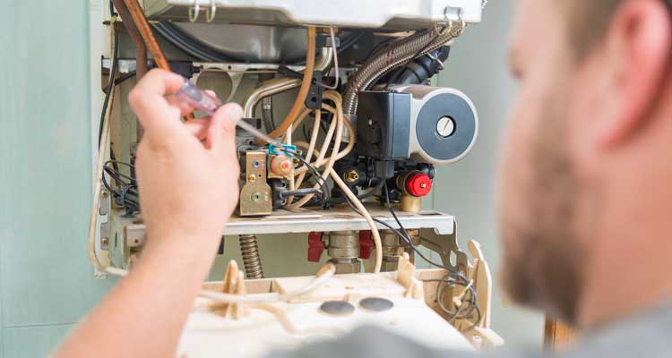 Pelican Heating & Air technician performing preventive maintenance on a boiler in a Bellevue, WA residential utility room