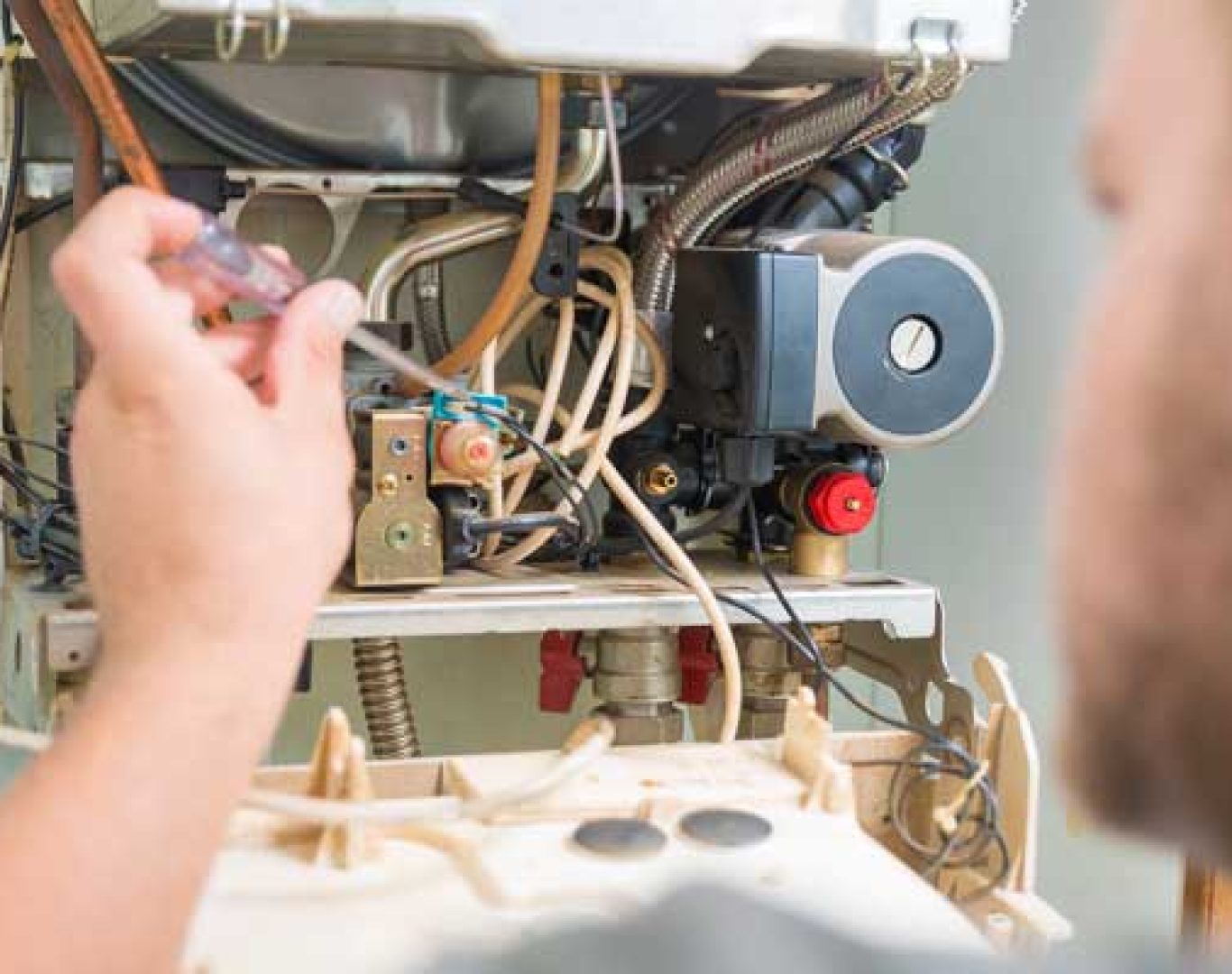 Pelican Heating & Air technician performing preventive maintenance on a boiler in a Bellevue, WA residential utility room